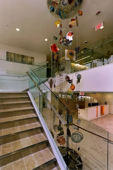 a staircase with glass railings and art pieces from the ceiling